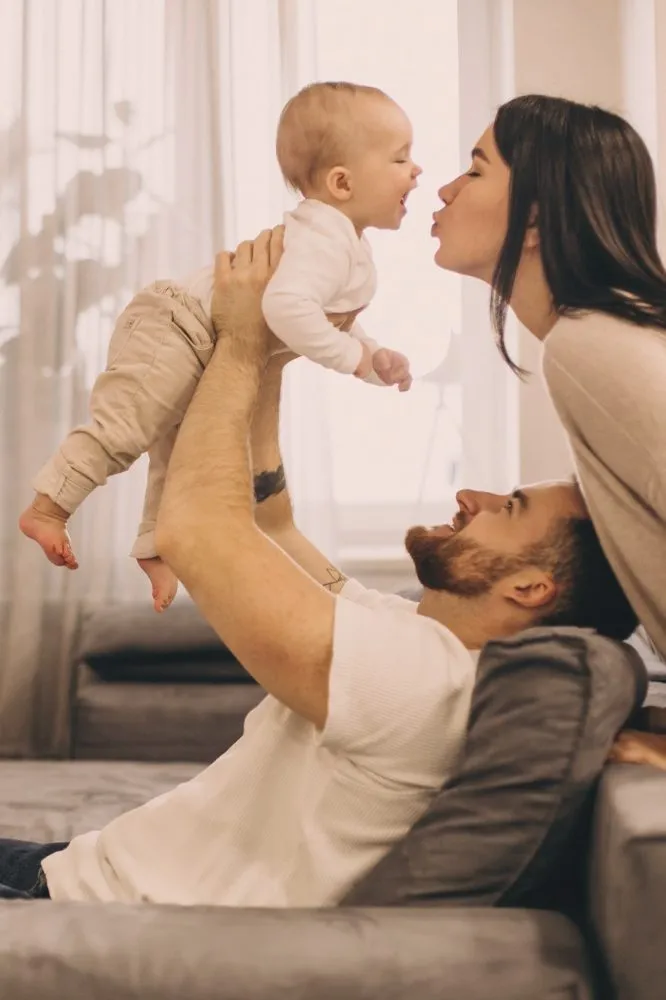 Parents playing with their baby on the living-room sofa