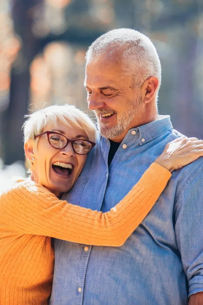 Older couple hugging and laughing outdoors in autumn