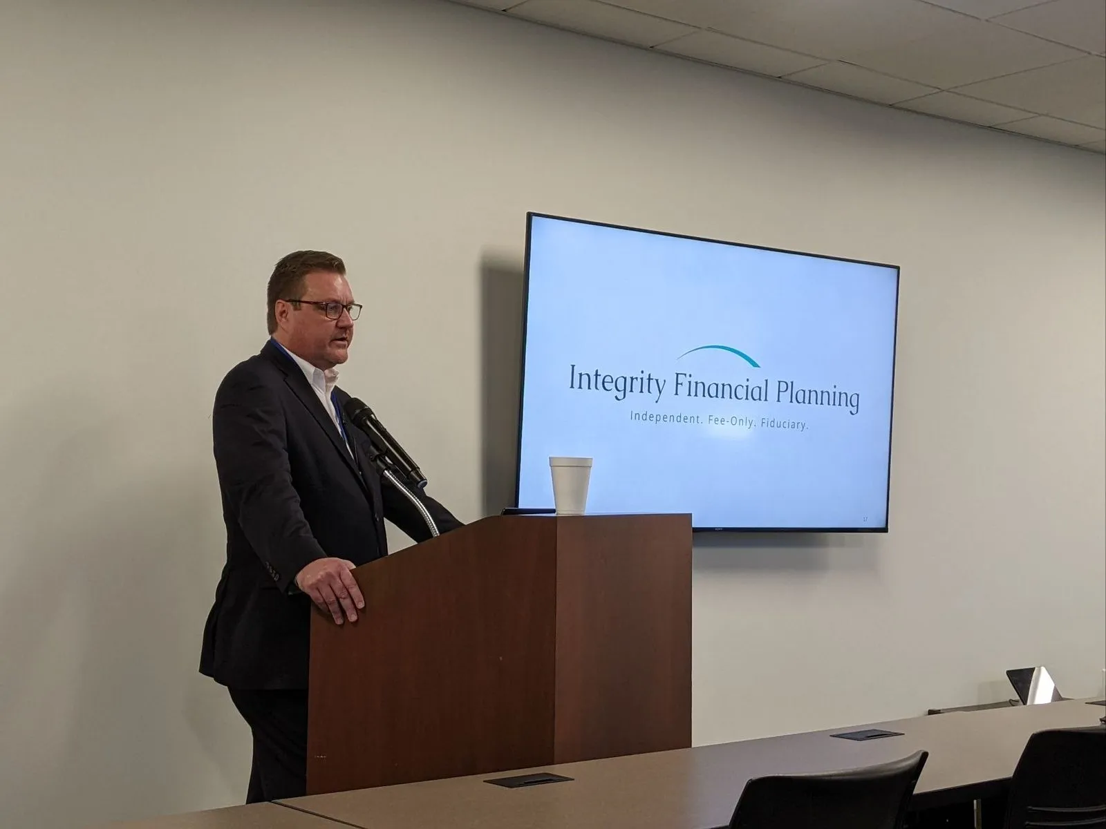 Todd Smurl presenting at a podium with the Integrity Financial Planning logo on screen